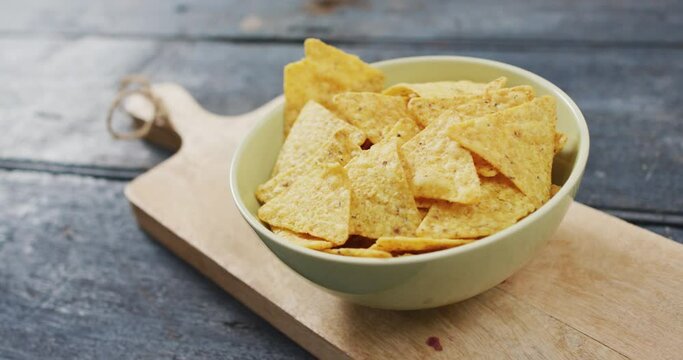 Close up view of bowl of nachos on wooden tray with copy space on wooden surface
