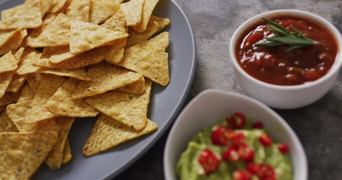 Close up of nachos in a plate and sauces on black surface