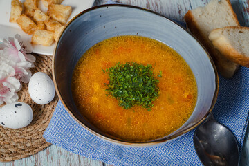  Chicken soup in a blue dish with greenes. Top view