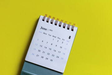 Desktop calendar for June 2022 on a yellow background.