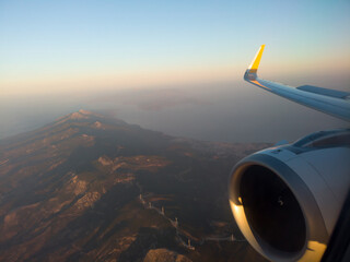 Naklejka na ściany i meble Airplane wing with engine out of window. Flight over land on sunrise. Airplane porthole view. Blurred image. Defocused.