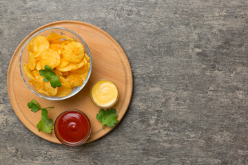 Top view chips with sause in bowl on colored background, top view with copy space