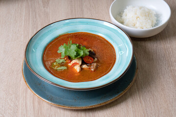 Red tomato soup with cilantro, shrimps and rice on the table