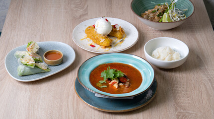 Red tomato soup with cilantro, shrimp and rice on the table, dessert with banana and ice cream and vegetable salad on a light table