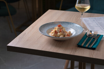 Dish with pasta and caviar on the table and a glass of white wine