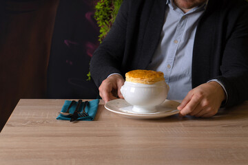 Man in shirt and jacket tasting soup with bread cover in a restaurant
