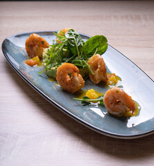 Shrimps on a gray dish with vegetable garnish and herbs