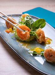 Shrimps on a gray dish with vegetable garnish and herbs
