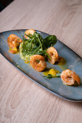 Shrimps on a gray dish with vegetable garnish and herbs