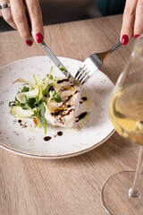 Girl cuts with a knife and fork Snack of cheese and nuts with sauce and salad