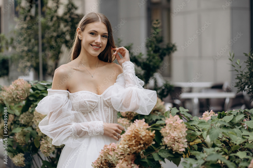 Wall mural portrait of pretty young bride in hydrangea blossom. wedding dress with neckline. wedding dress with