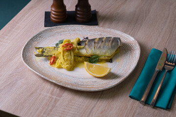 Baked sea bream with vegetables on a dish on a table in a restaurant