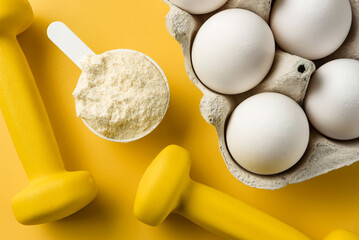 Protein scoop, egg packaging and dumbbells close-up. The concept of sports nutrition.