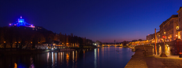 Turin, Italy. February 15, 2022. View of the Po river at night with the Church of Santa Maria del Monte dei Cappuccini on the left and Umberto I Bridge at the center. Header banner image.