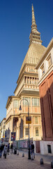 Turin, Italy. February 15, 2022. Vertical panoramic view of the Mole Antonelliana, home of the National Cinema Museum, taken from Via Montebello where some people are walking.