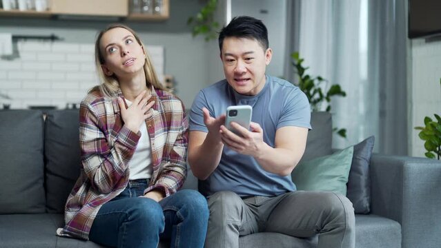 Married couple, man and woman, sitting on the couch at home and arguing over the phone, jealousy. Young family Marital infidelity, Adultery, secret correspondence mistrust of partners and quarrels