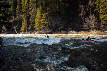 Mountain river turbulent flow, kayaking on the waves, athletes kayakers swim along the mountain...