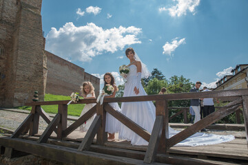 The bride and two little girls in a white dress on a wooden bridge in the old city.