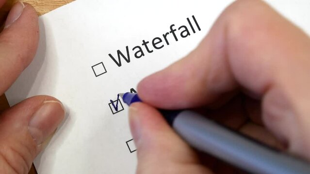 Hand daw in the questionnaire. A closeup of female hand answering about waterfall, agile, kanban question marking in a checkbox
