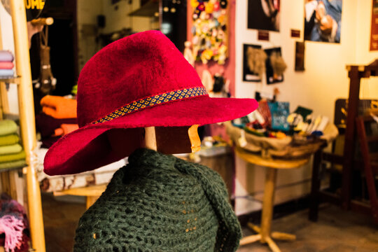 red hat made in filter based on alpaca fiber with ancestral designs and geometric figures in bright colors arranged on a table with a white tablecloth - Powered by Adobe