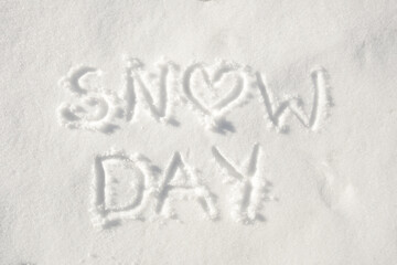 Text "snow day" written in snow, with a heart for letter o; concept of a happy day off because of snowy weather