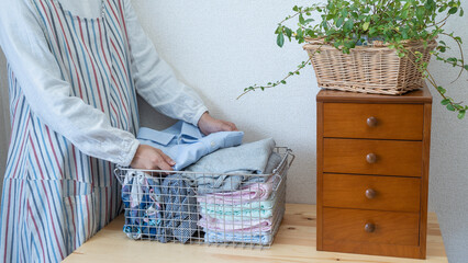 ワイヤーバスケットに洗濯物を入れる女性