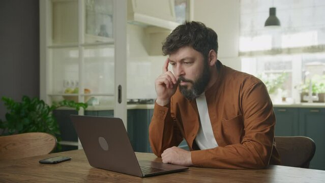 A thoughtful businessman is upset by the stock market crash in front of his laptop