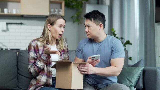 shocked frustrated couple customer open cardboard box receive wrong or damaged shopping order parcel. Sad young asian man and woman unpacking wrong parcel, delivery mistake Upset mad asia people
