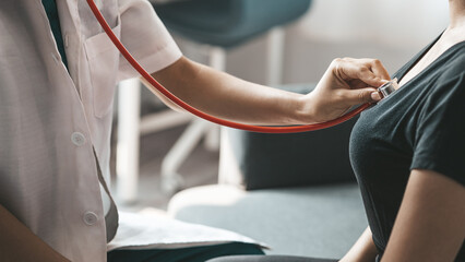 A female doctor using a stethoscope, she is examining the patient in the examination room and informing the patients about treatment guidelines and prescribing medicines. Disease examination concept.