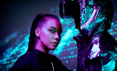 Portrait of young woman being part of virtual reality environment standing at unrecognizable person...