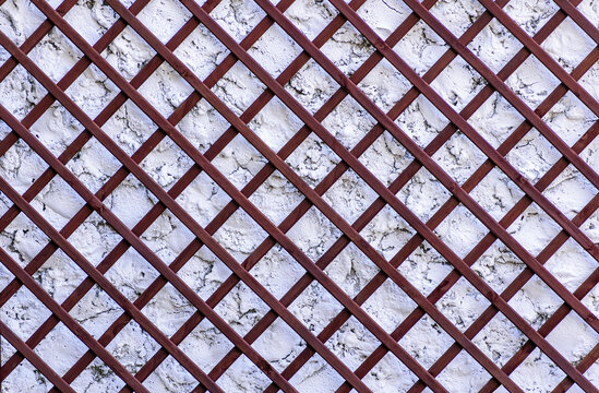 Wooden lattice on the old wall, with an uneven surface.
