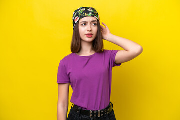 Young Ukrainian woman isolated on yellow background having doubts