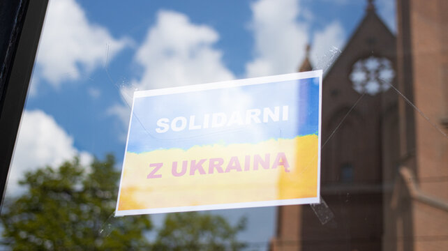 Yellow blue flag poster with inscription solidarni z ukraina translated from polish in solidarity with Ukraine, pasted on a glass shop window. The concept of patriotism and support from Poland