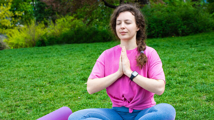 Calm young woman with closed eyes sitting in lotus pose, practicing yoga breathing techniques on...