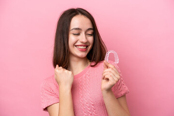 Young Ukrainian woman holding invisible braces isolated on pink background celebrating a victory - obrazy, fototapety, plakaty