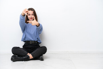 Young Ukrainian woman sitting on the floor isolated on white background focusing face. Framing symbol