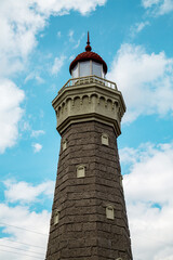 Obraz premium View of the ancient gray stone lighthouse on a clear sunny day against the blue sky. Medieval architecture, world tourism.