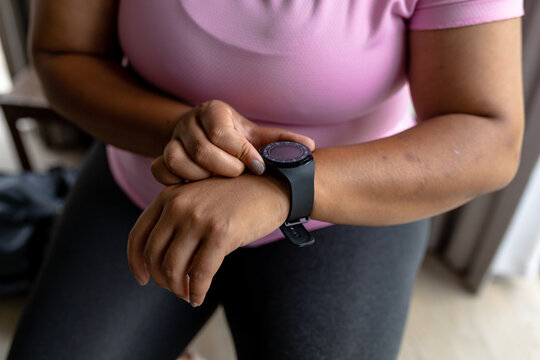 Midsection of african american mid adult woman checking time while sitting at home