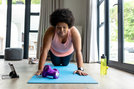 African american mid adult woman doing push-ups while using digital tablet at home