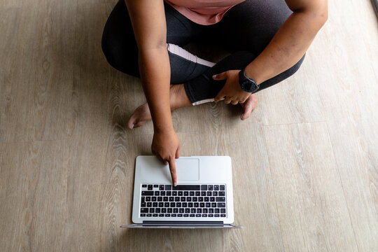 Low section of african american mid adult woman using laptop while sitting on laptop at home