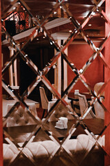 modern restaurant in antique style. columns inside the restaurant. many mirrors. red and yellow decor. warm tones. expensive restaurant.