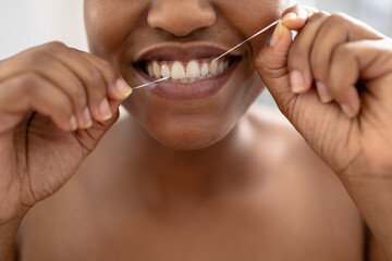 Obraz premium Close-up of african american mid adult woman using dental floss in bathroom