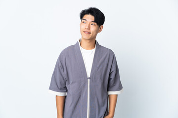 Young Chinese man isolated on white background thinking an idea while looking up