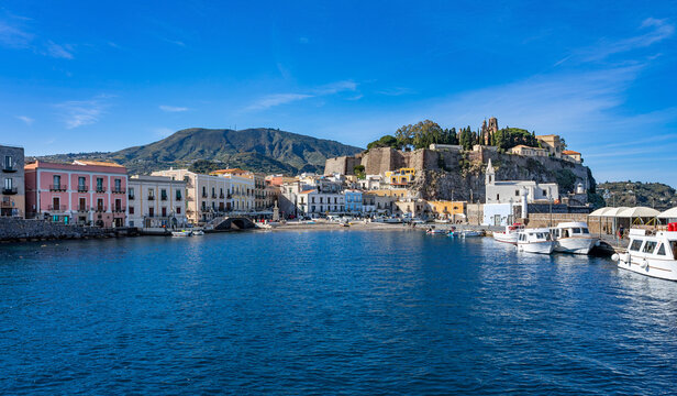 Sizilien: Lipari Stadt - der alte kleine Hafen vom Boot, Wasser aus betrachtet mit Kirche, Burgberg, Kastell, historischen Geb&auml;uden und Booten