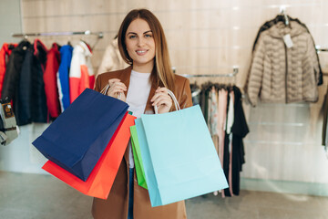 Happy young woman holding shopping bags in clothing store. Shopping concept. Sale