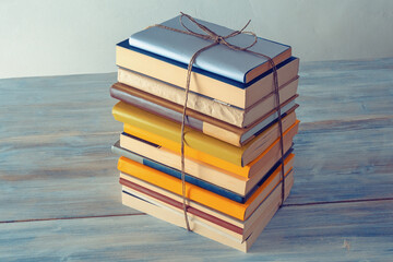 Vertical stack of  books tied with rope on rustic table.  Free space for text