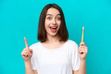 Young Ukrainian woman brushing teeth isolated on blue background pointing up a great idea