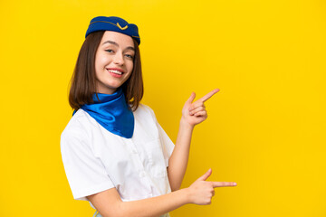 Airplane stewardess Ukrainian woman isolated on yellow background pointing finger to the side and presenting a product