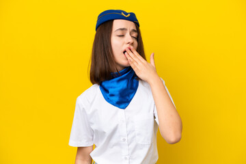 Airplane stewardess Ukrainian woman isolated on yellow background yawning and covering wide open mouth with hand