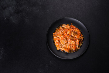 Teriyaki chicken with sauce, sesame, herbs and spices on a dark background